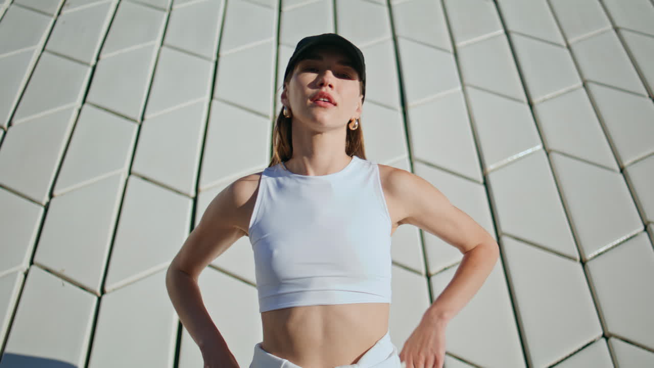Stylish sportswoman posing city tiled wall closeup. Confident woman relaxing