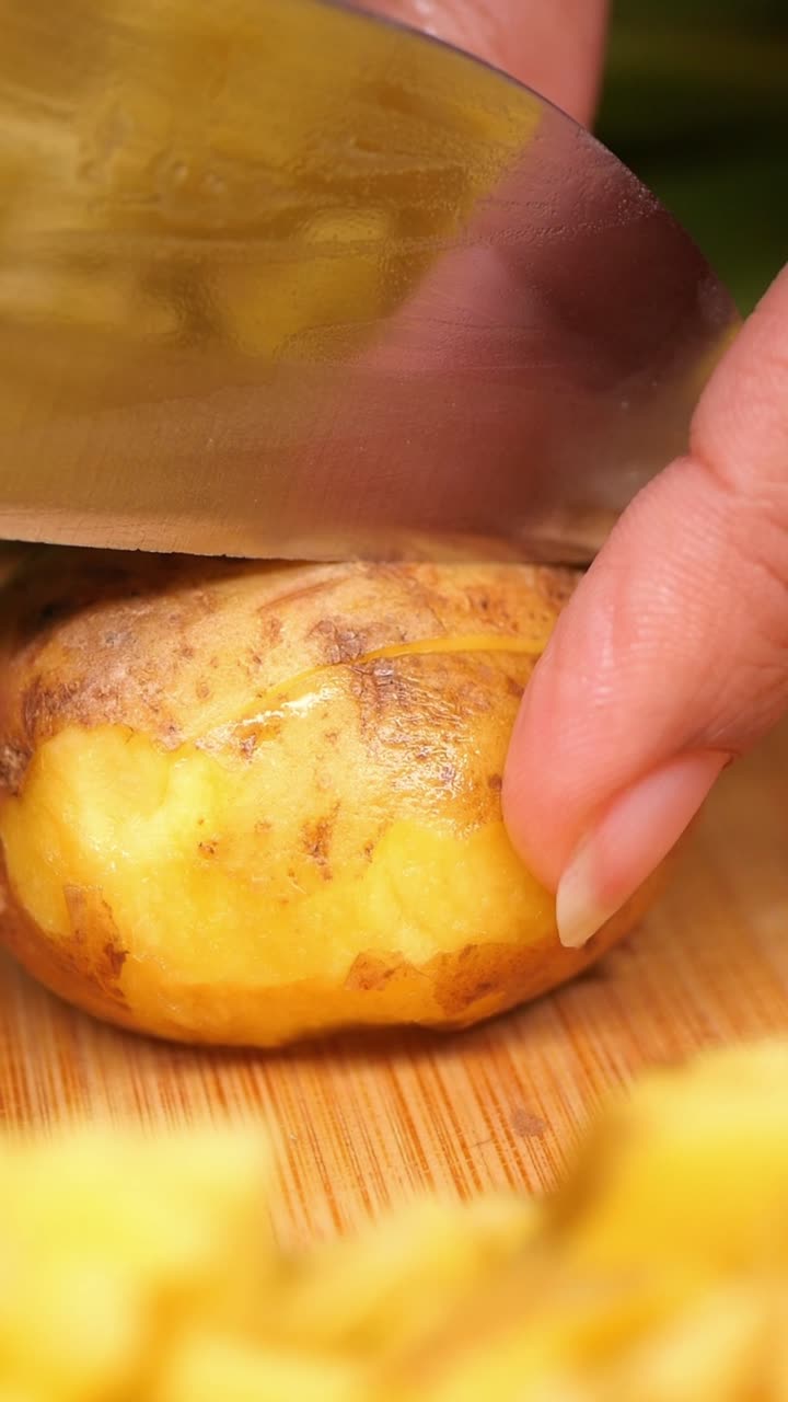 Primo piano di mano che sbuccia una patata con un coltello