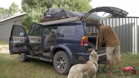 Hombre-Con-Perro-Aspirando-Dentro-De-Un-Sucio-Vehículo-De-Limpieza-Suv-Después-De-Un-Viaje-Por-Carretera