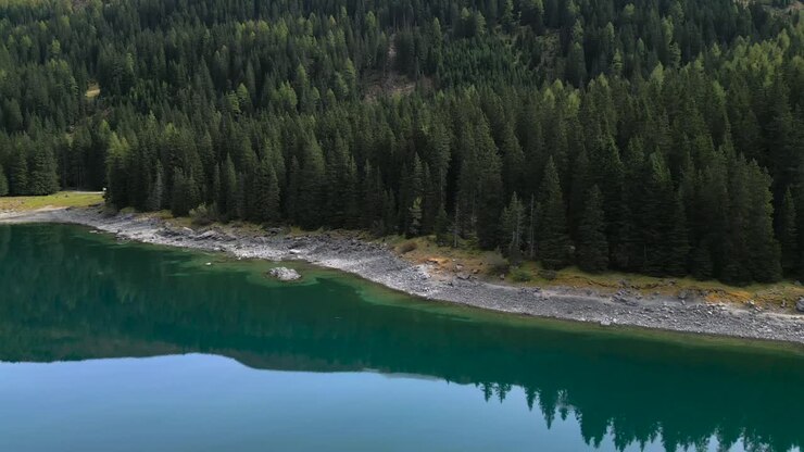 Riprese drone della sponda del lago Obernberger nel Tirolo austriaco con acqua blu molto limpida e riflessi delle montagne