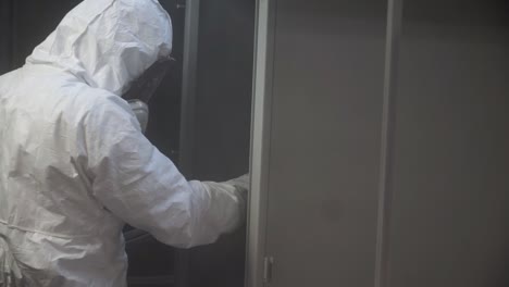 trabajador con equipo de protección pintando con spray metálico