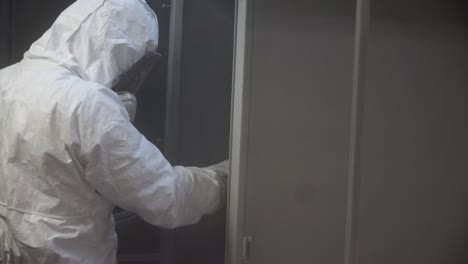 worker in protective gear spray painting metal