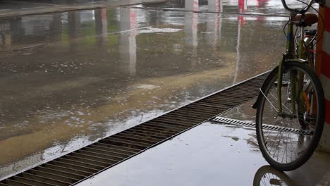 pour rain by puddles on cement ground of urban parking with bicycle wheel