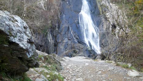 rocky cascading waterfall flowing into jagged river rocks dolly left to boulder