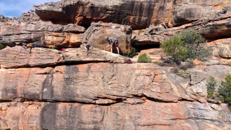 Male-rock-climber-standing-on-a-rocky-mountain-4k