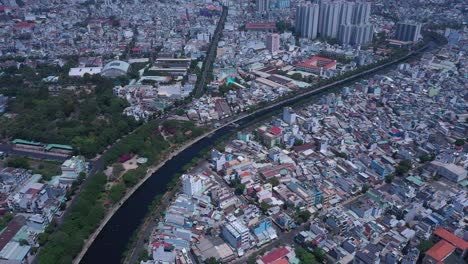 Ho-Chi-Minh-City,-Vietnam,-aerial-view-on-a-sunny-day-featuring-canal,-rooftops,-green-space-and-urban-sprawl-in-district-six