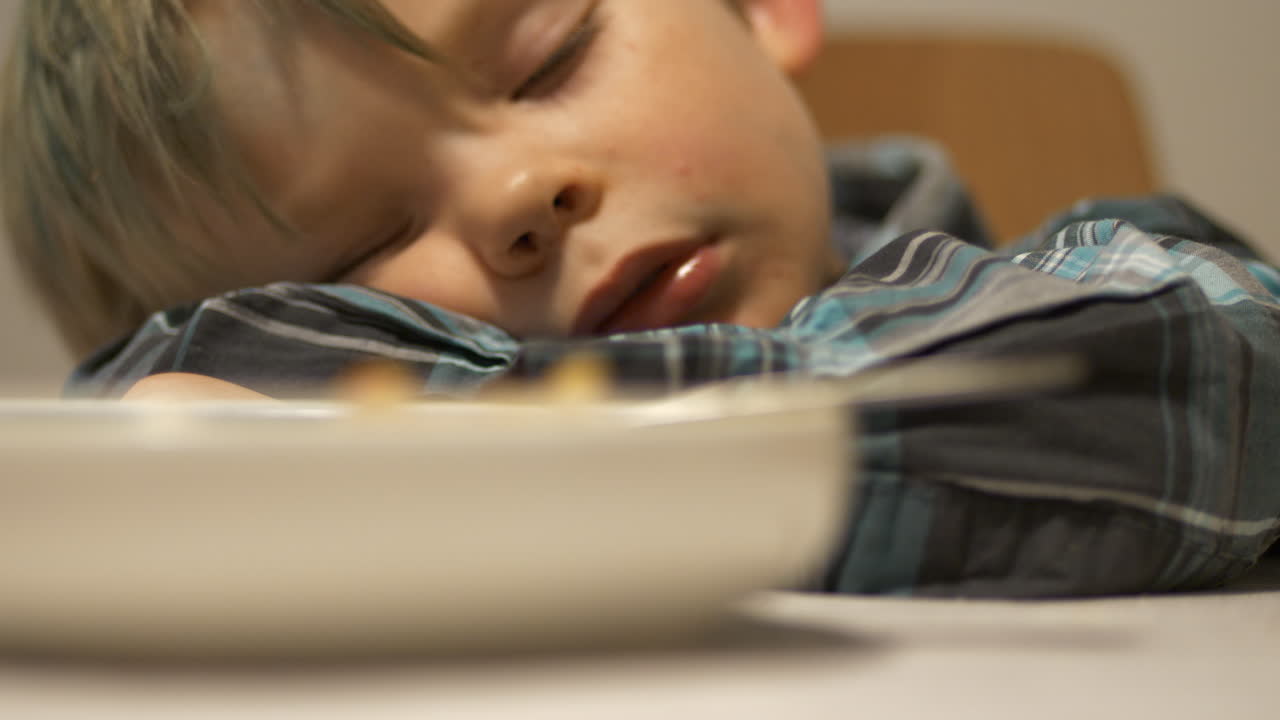 niño hermoso niño está durmiendo en la mesa de comedor con comida en el plato