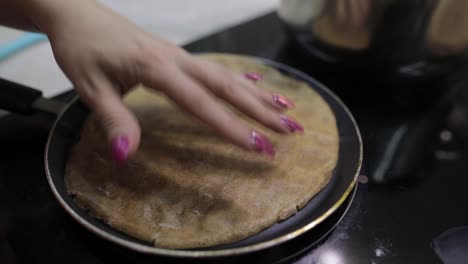 The-process-of-cooking-homemade-pancakes.-Woman-turns-pancake-in-a-frying-pan