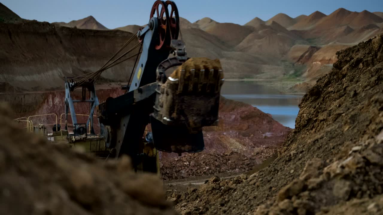 Time lapse of excavator loading ore into dump-trucks at the sunset.