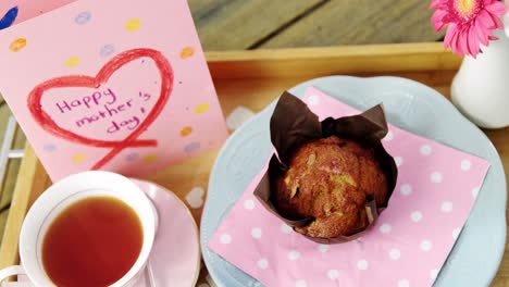 cupcake, tea, flower vase and happy mothers day greetings card in tray