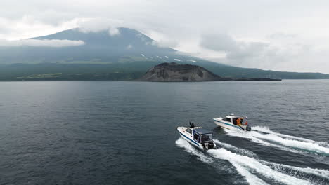 two boats sail towards an island in the pacific ocean