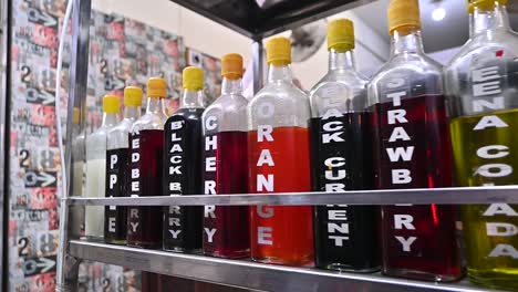 creative handheld shot across row of different flavoured syrup bottles on cart in street