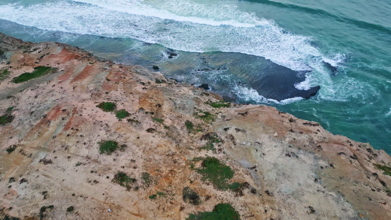 Ripresa da drone in primo piano di un paesaggio naturale con pendii sabbiosi. Schiuma del surf oceanico sotto un cielo cupo.
