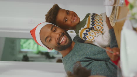 vertical video of father in santa hat with children enjoying eating christmas meal at home together