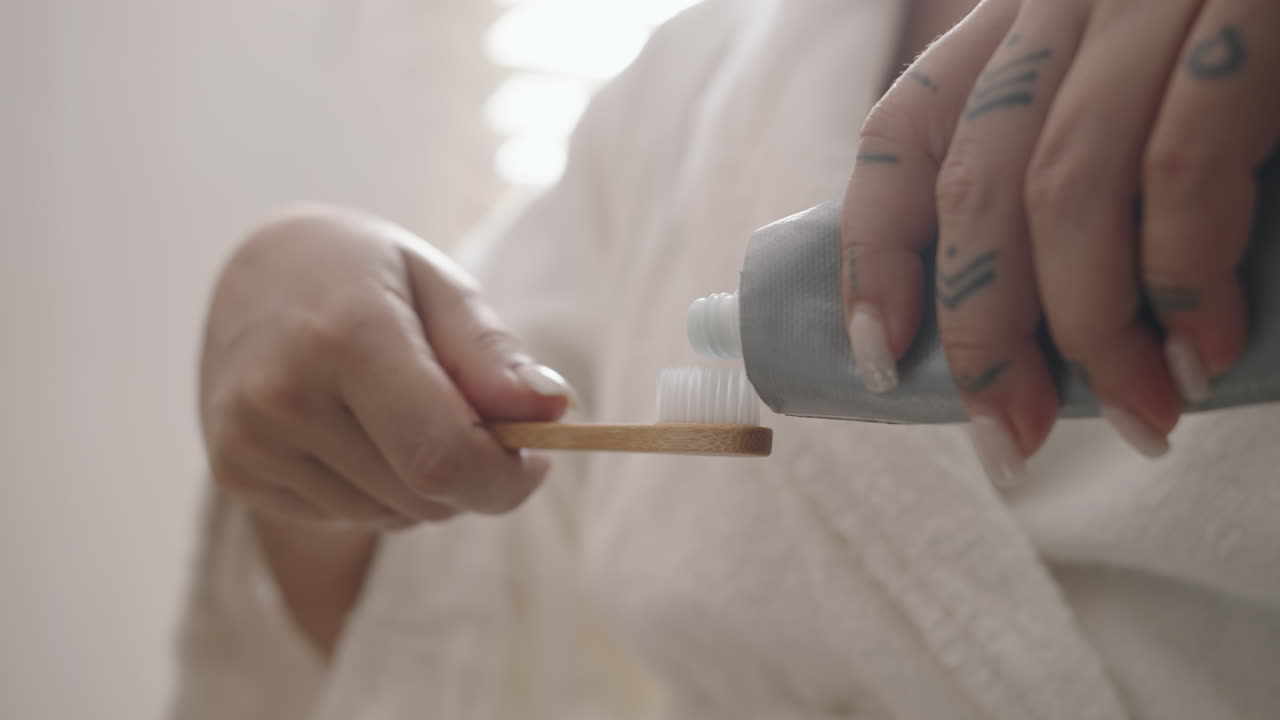 Hands of Woman Squeezing out Toothpaste on Toothbrush