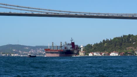 cargo ship passing under fatih sultan mehmet bridge, bosphorus, istanbul, turkey