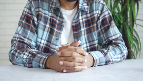 hombre sentado en la mesa con las manos en el regazo