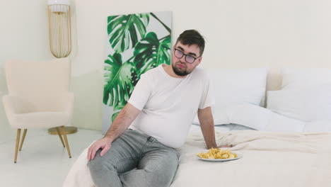 niño sentado en la cama y comiendo papas fritas