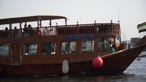 large boat driving down dubai creek with tourists on board