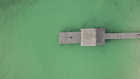 Aerial-view-of-a-young-girl-laying-on-a-jetti-at-Pigeon-Point,-Tobago