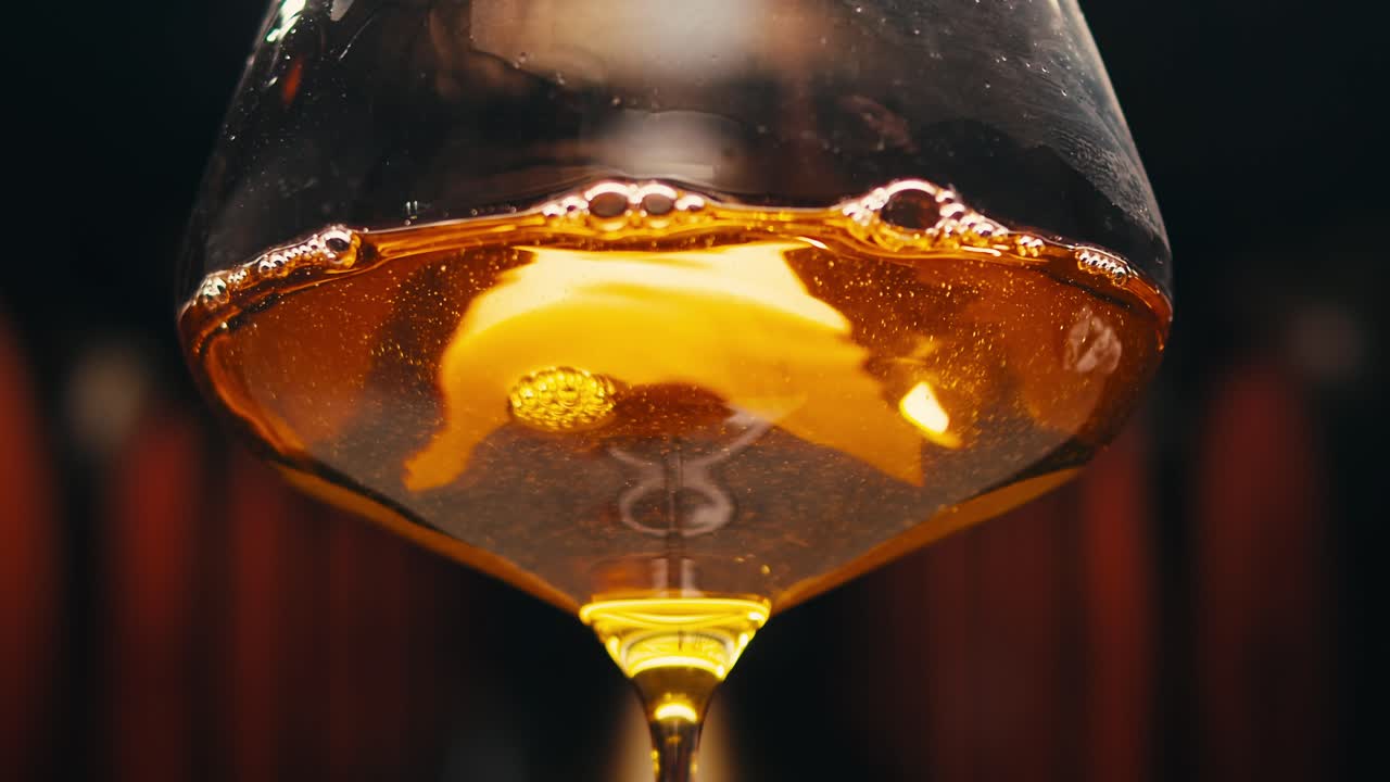 Orange or white wine bottle and glass against a sunset in a peaceful vineyard, pouring of ecological natural wine.