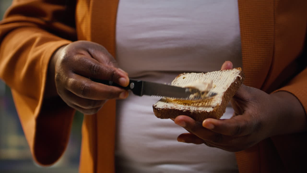 Close up of food vlogger spreading butter cream on a toast slice
