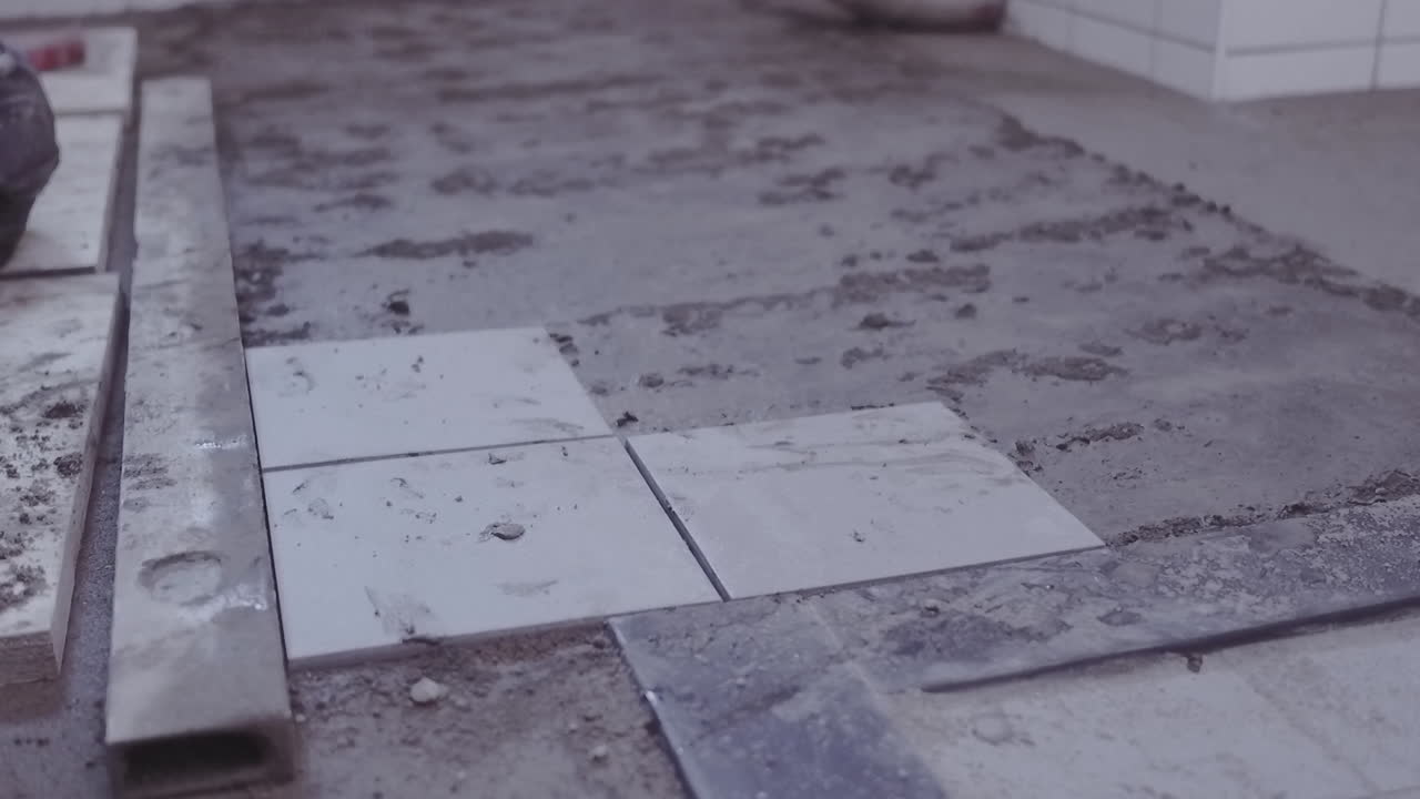 Laying the first three floor tiles during a bathroom renovation