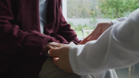 midsection of asian female physiotherapist treating hand of senior female patient at surgery