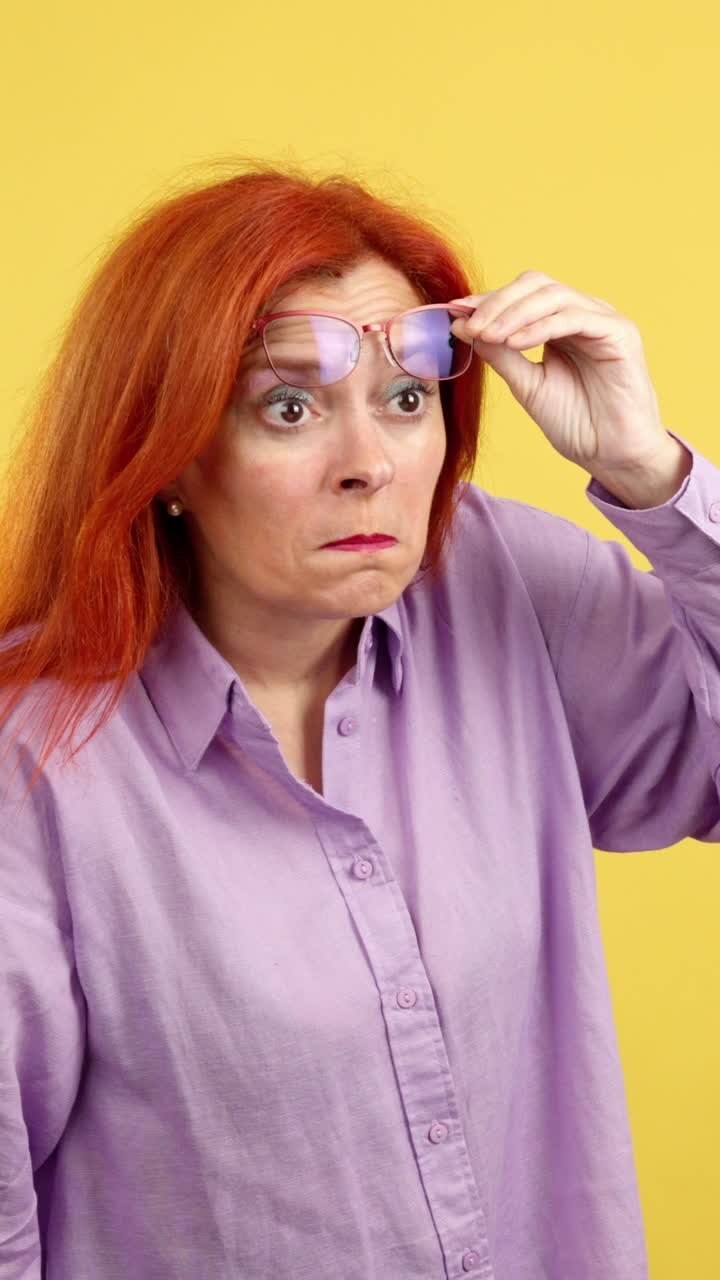 Woman squinting and holding glasses up