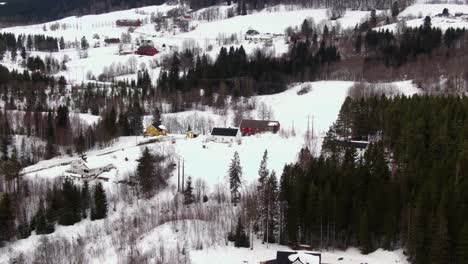 rural winter area with houses surrounded by snow, hills and trees