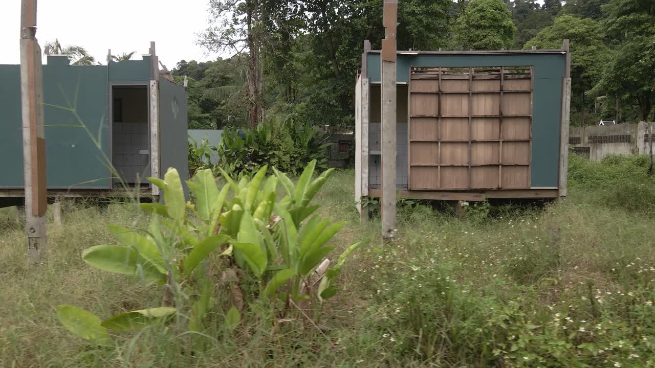 tiro de camión en movimiento a la izquierda de un complejo de playa de bungalows abandonado y destruido por los efectos en el turismo de covid 19