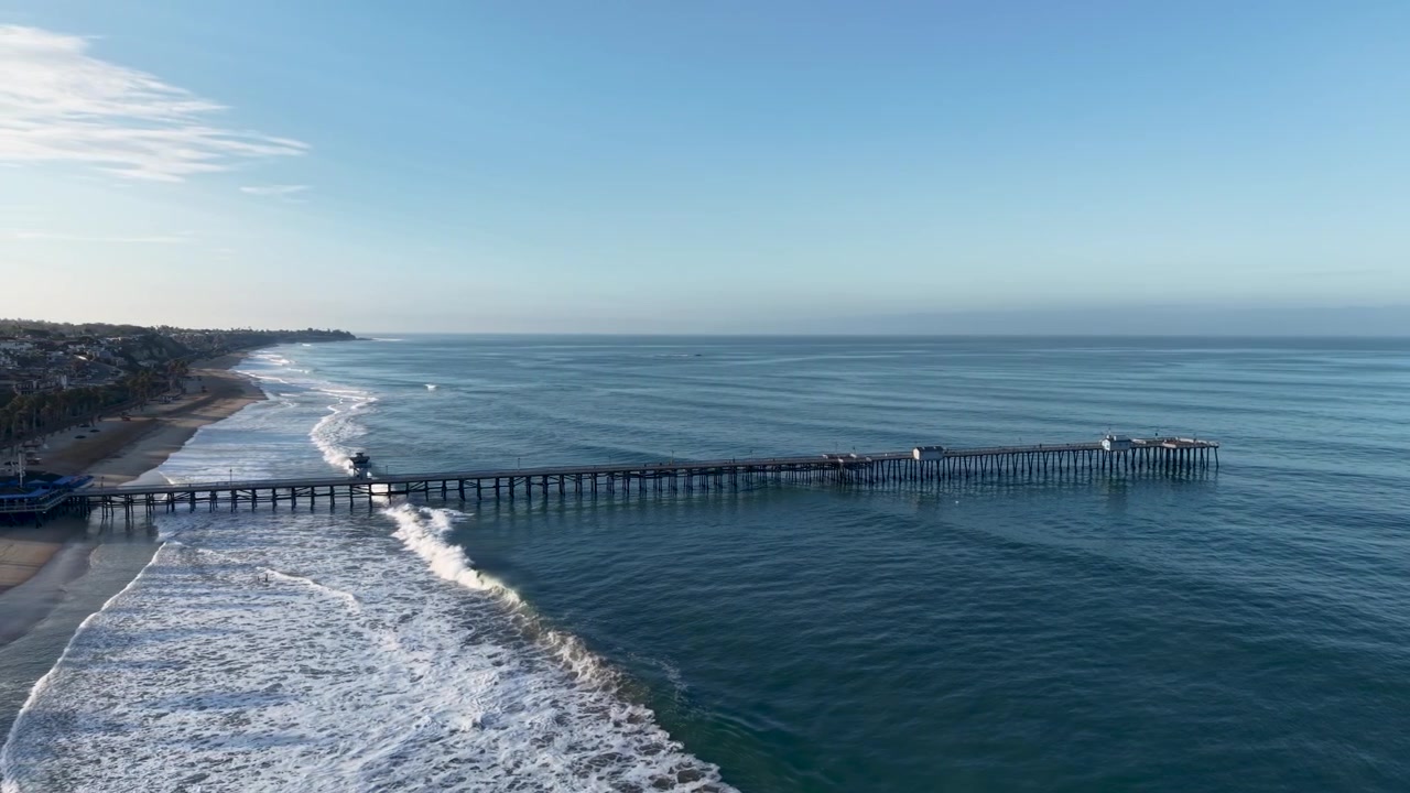 Una vista aerea mozzafiato ad alta quota dell'iconico molo di San Clemente mentre il drone sorvola elegantemente dalla costa all'Oceano Pacifico aperto