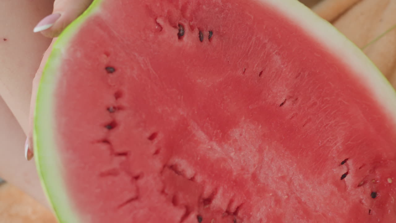 Chef prepares watermelon halves for summer feast, Closeup of kitchen chef cutting ripe watermelon for meal, Casual summer gathering as chef slices vibrant red watermelon halves for refreshing salad