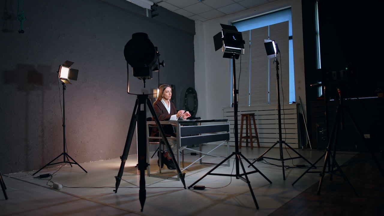 Soffits surround the lady sitting at desk in photo studio. Process of recording a blog or program.
