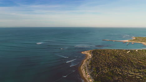 aerial - long waves rolling past old harbour and around point, rotating drone