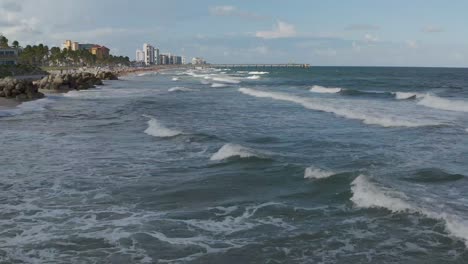 Aerial-moving-along-the-coastline-up-close-as-the-weeks-break-on-shore