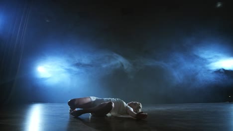 modern ballet dancing woman barefoot lying on the floor doing spins and pirouettes and somersaults