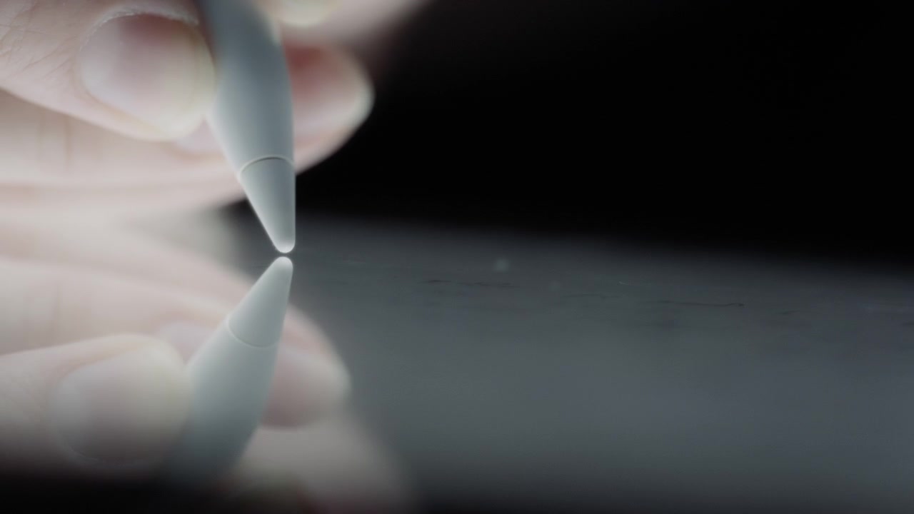Close up of a hand holding a pen and writing on a tablet