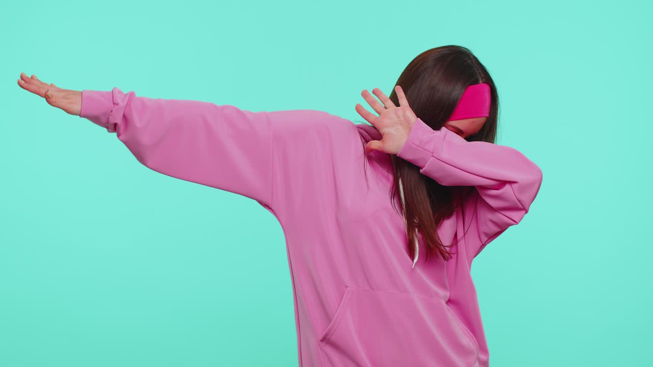 Trendy cheerful girl dancing and moving to rhythm dabbing raising hands making dubdance gesture