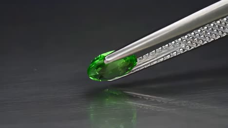 natural tsavorite green oval cut garnet in the tweezers