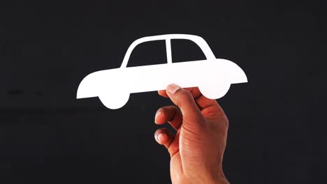 Hand-holding-paper-cut-out-of-a-car