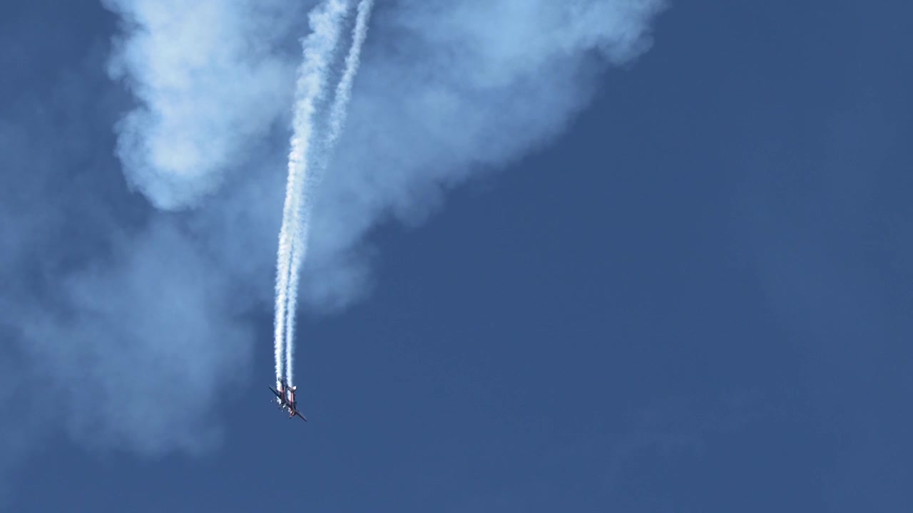 澄み渡る青空を急降下し、白い濃いスモークの軌跡を描く曲技飛行機