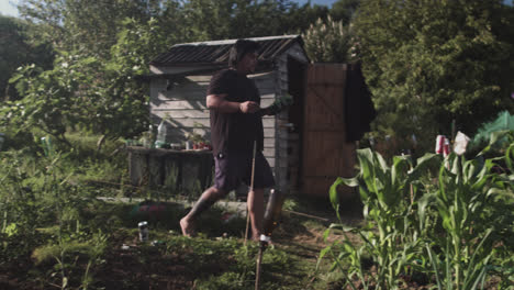 full shot of a latin man walking barefoot through his vegetable garden with small pots in his hand