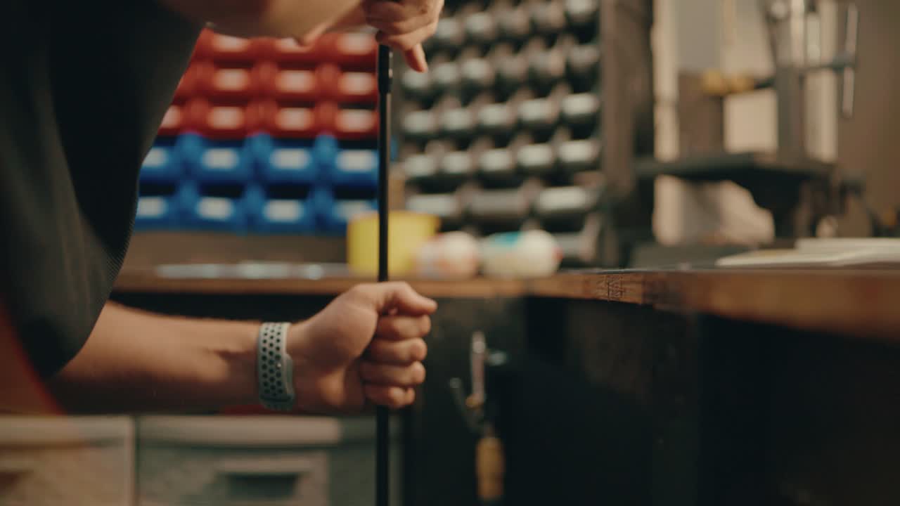 Male hands press golf club shaft down on ground for custom fitting in workshop in slow motion