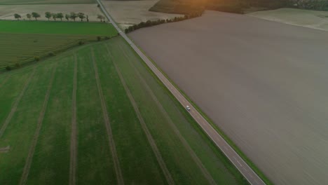 Luftdrohnenaufnahme-Eines-Autos,-Das-Auf-Einer-Autobahn-Fährt,-Mit-Blick-Auf-Die-Felder-Auf-Beiden-Seiten