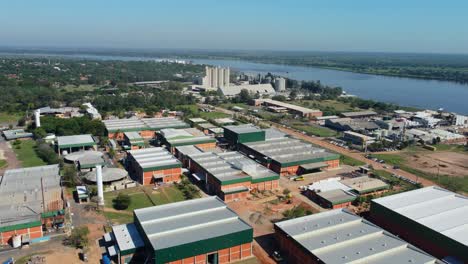 Industrial-buildings,-warehouse-next-to-a-river-from-aerial-view-with-rotating-motion