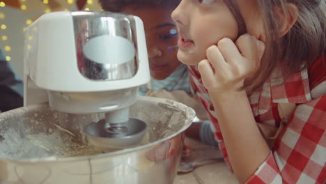 los niños viendo la mezcladora de pie amasar la masa en la clase magistral de cocina