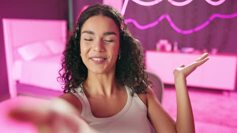 woman with curly hair smiling in her bedroom
