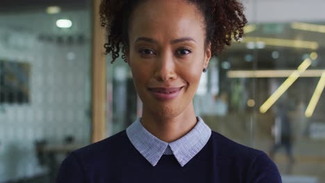 Portrait-of-smiling-mixed-race-businesswoman-in-blue-jumper-standing-in-office