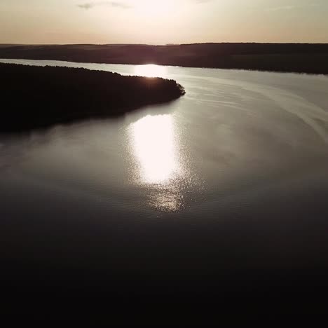 wide river is flowing at sunset in the summer. sun's rays are reflecting in the water of the lake. aerial view